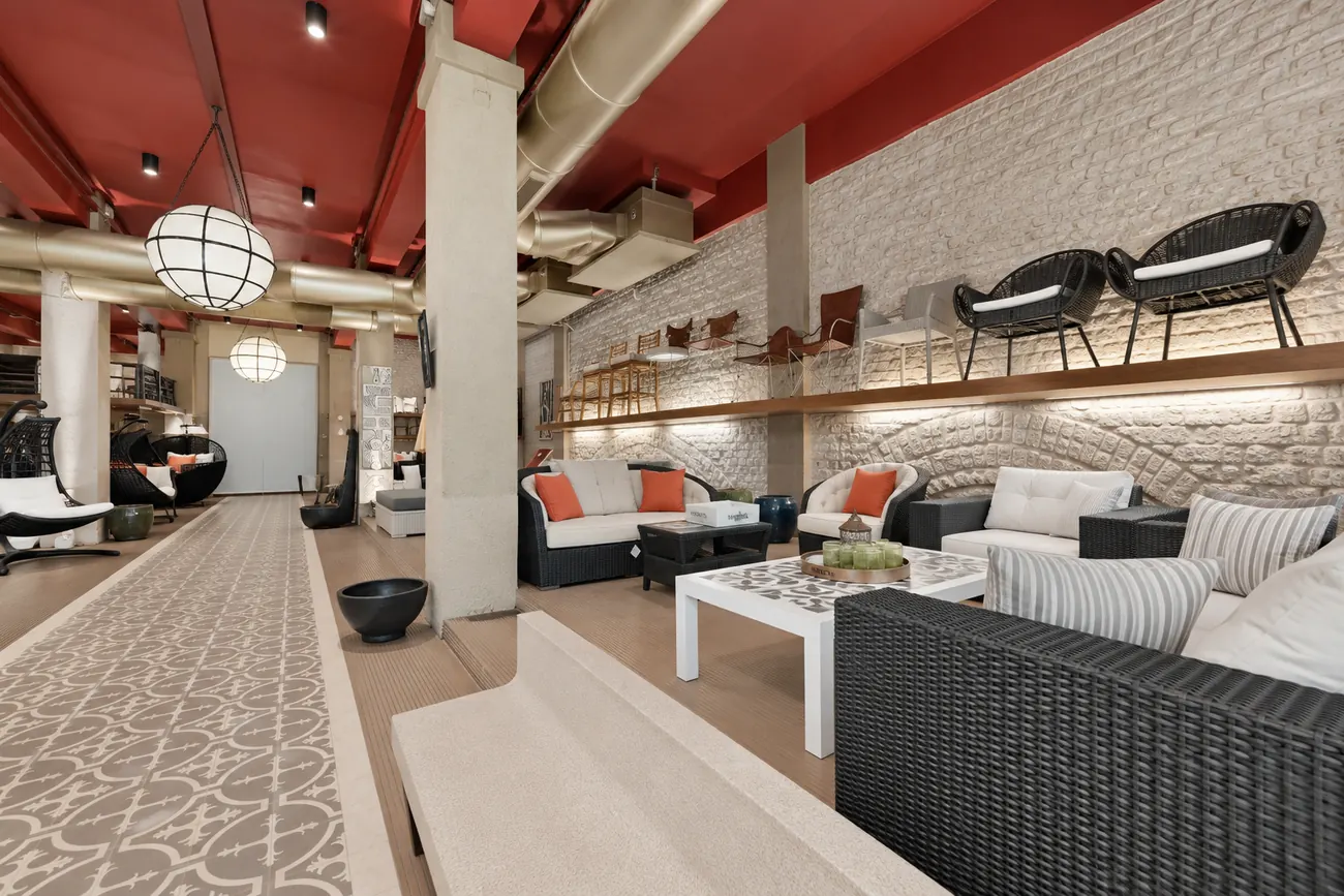 Brick wall shelving at Abaca lined with outdoor chairs, beside a lounge seating area on a patterned rug.