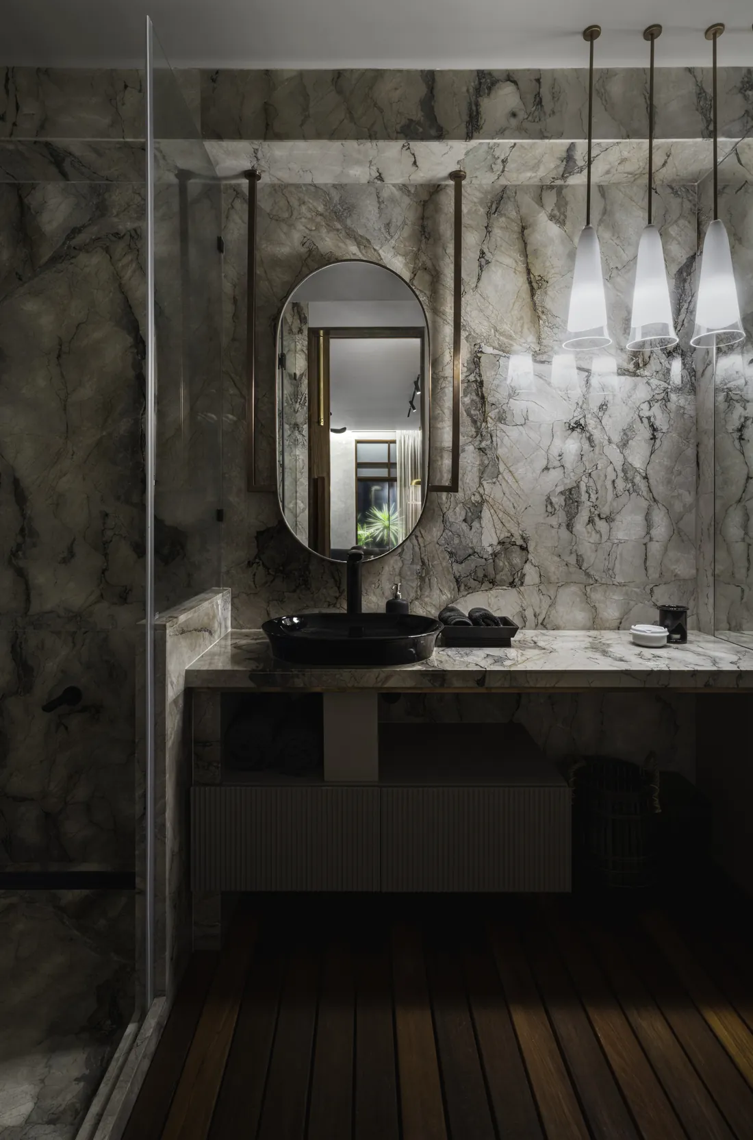 Grey stone-clad bathroom at Cambridge Court with a round backlit mirror, wall-mounted toilet and a vessel sink on a timber vanity.