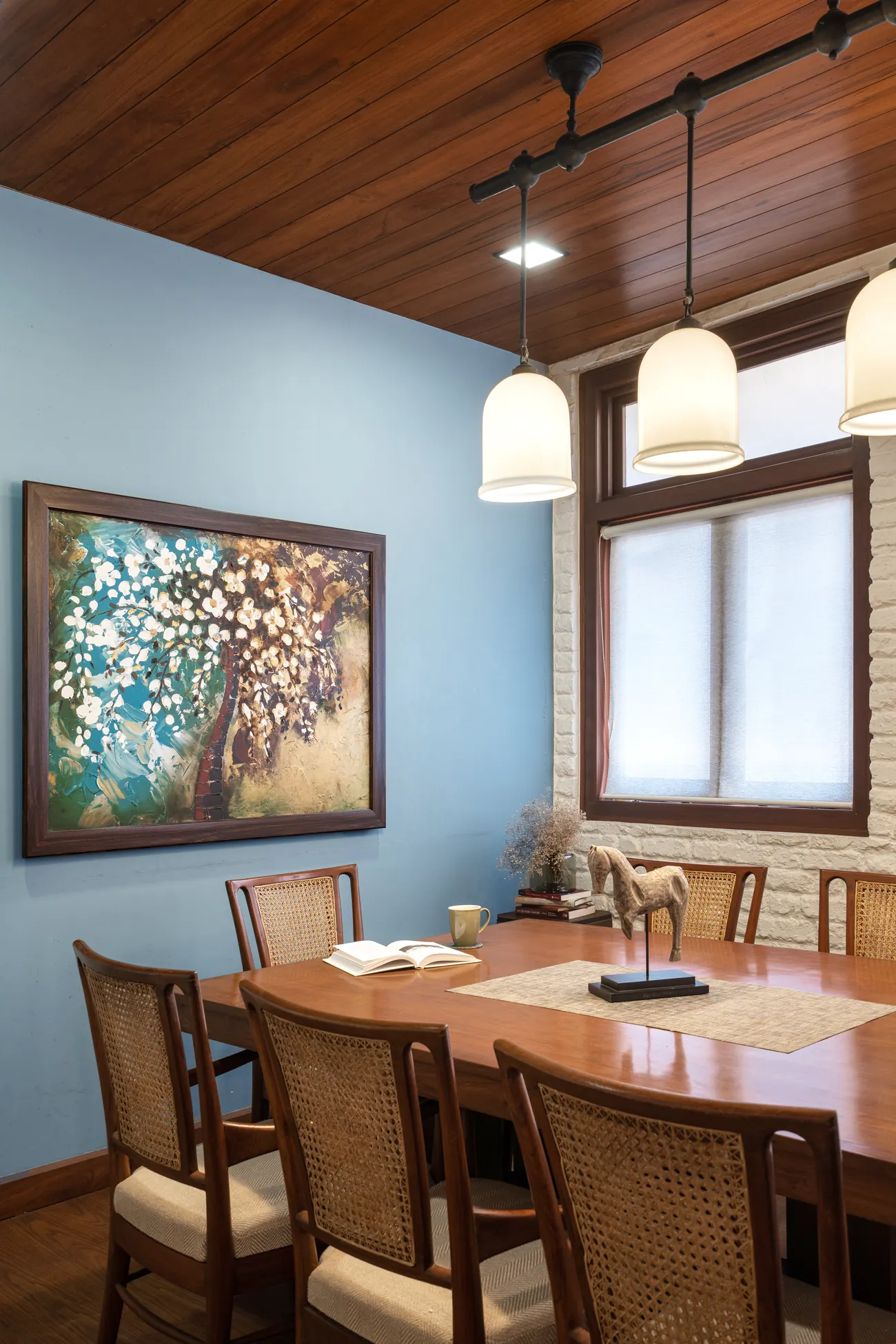 Blue-walled room at Lawyers Chambers with a cane sofa, framed artwork and a glimpse into the library beyond.