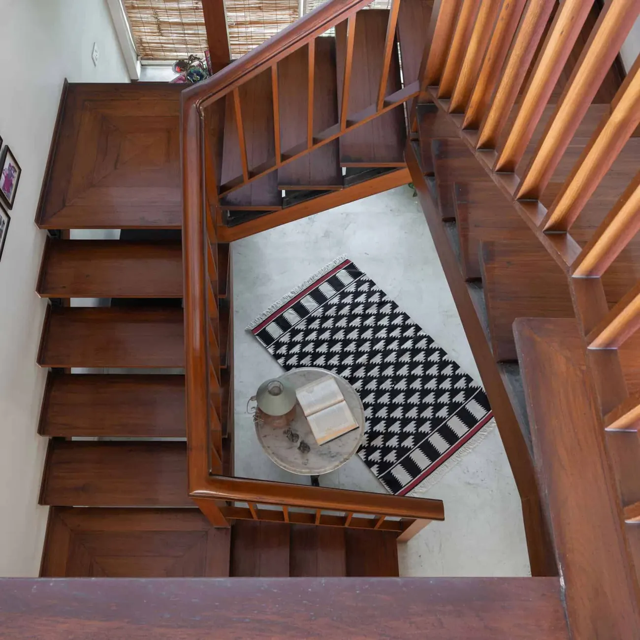 The staircase at Lloyds Gardens seen from above, with a woven black-and-white rug and a marble side table on the floor below.