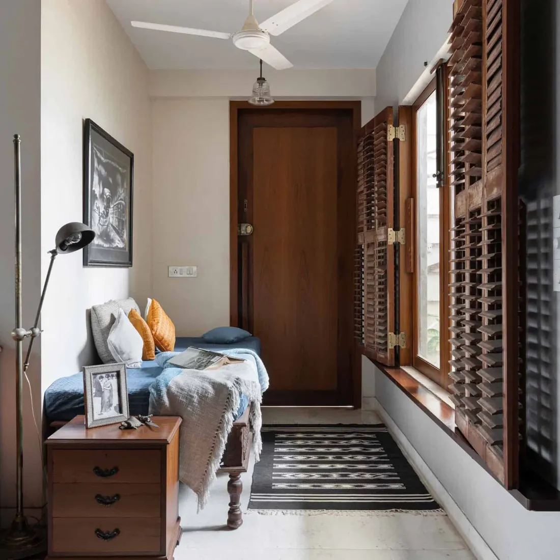 Daybed room at Lloyds Gardens with a teak chest of drawers and old louvred timber shutters folded back from the window.