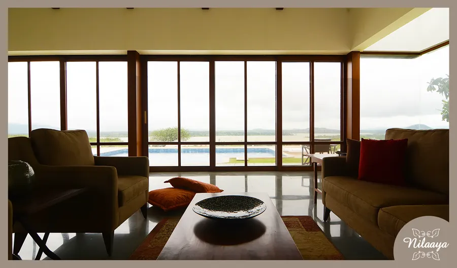 Living room at Nilaaya with full-height glazing looking out over the swimming pool and the hills beyond.