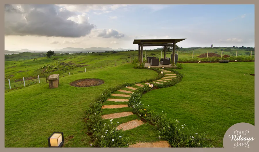 Gazebo and stepping-stone garden path at Nilaaya, set on open lawns with hills in the distance.