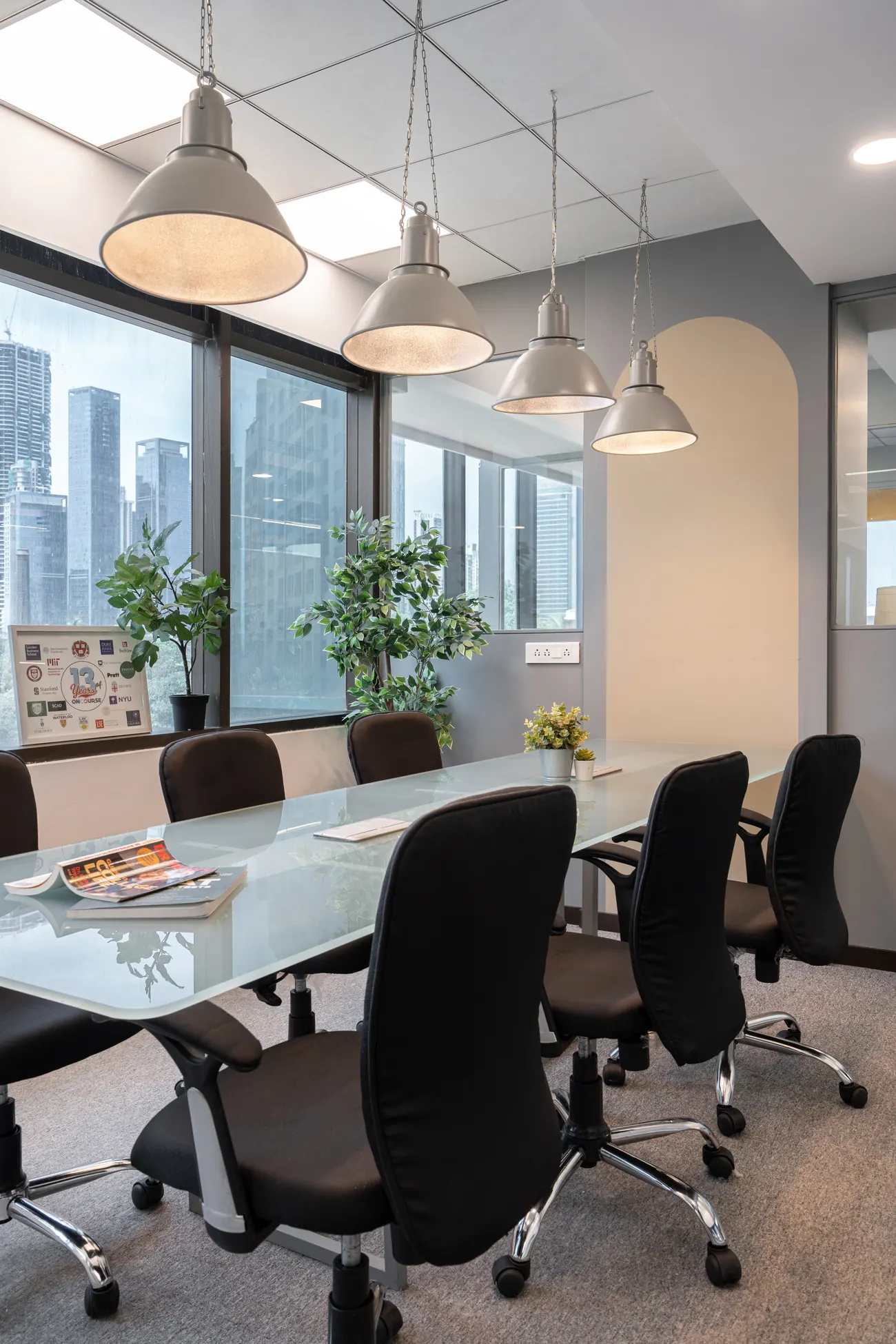 Meeting room at OnCourse with a glazed steel-framed partition, exposed brick wall and a hanging Cambridge sign.