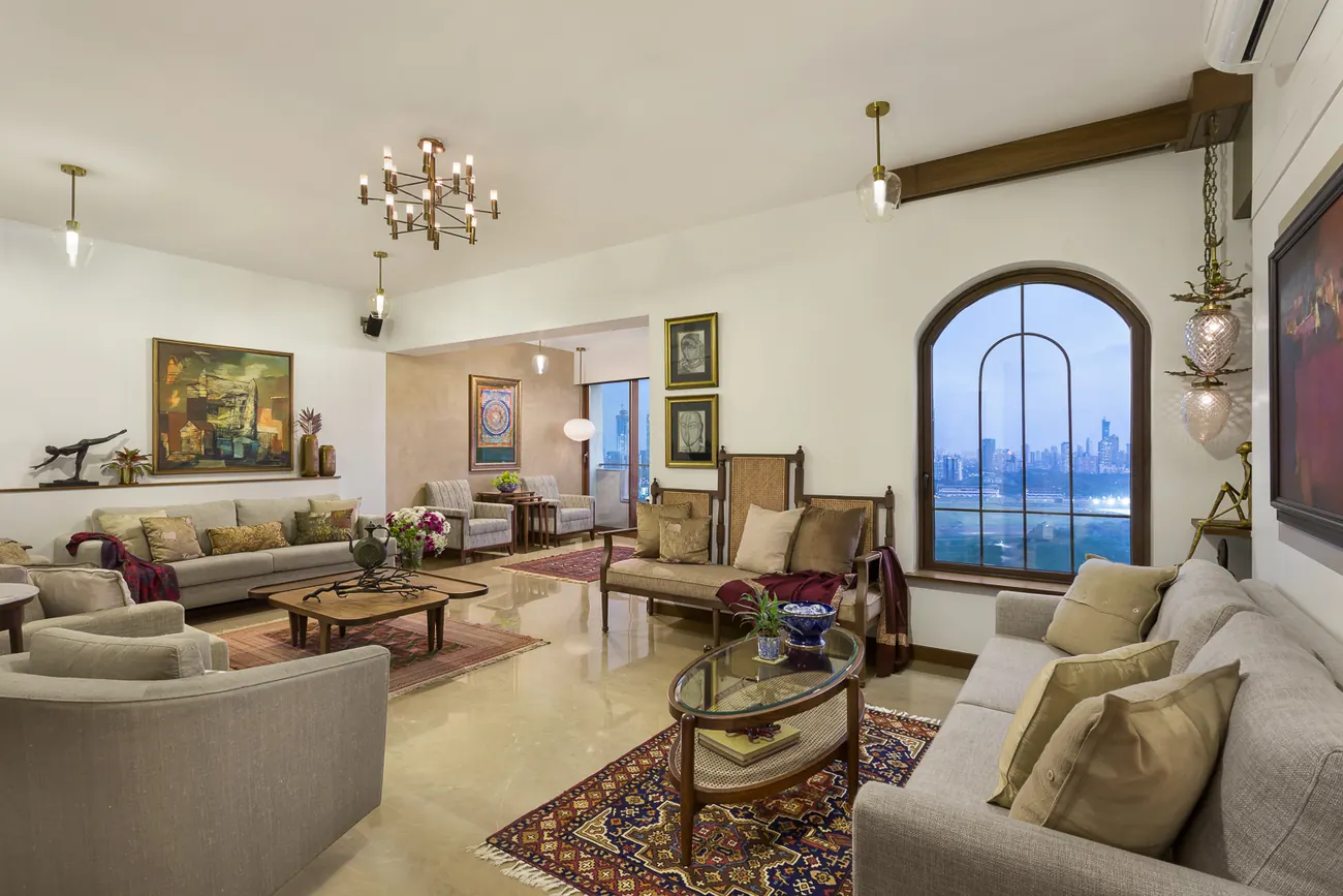 Living room at Zara at dusk, seen through an arched window, with sofas and a textile runner leading to the dining area.
