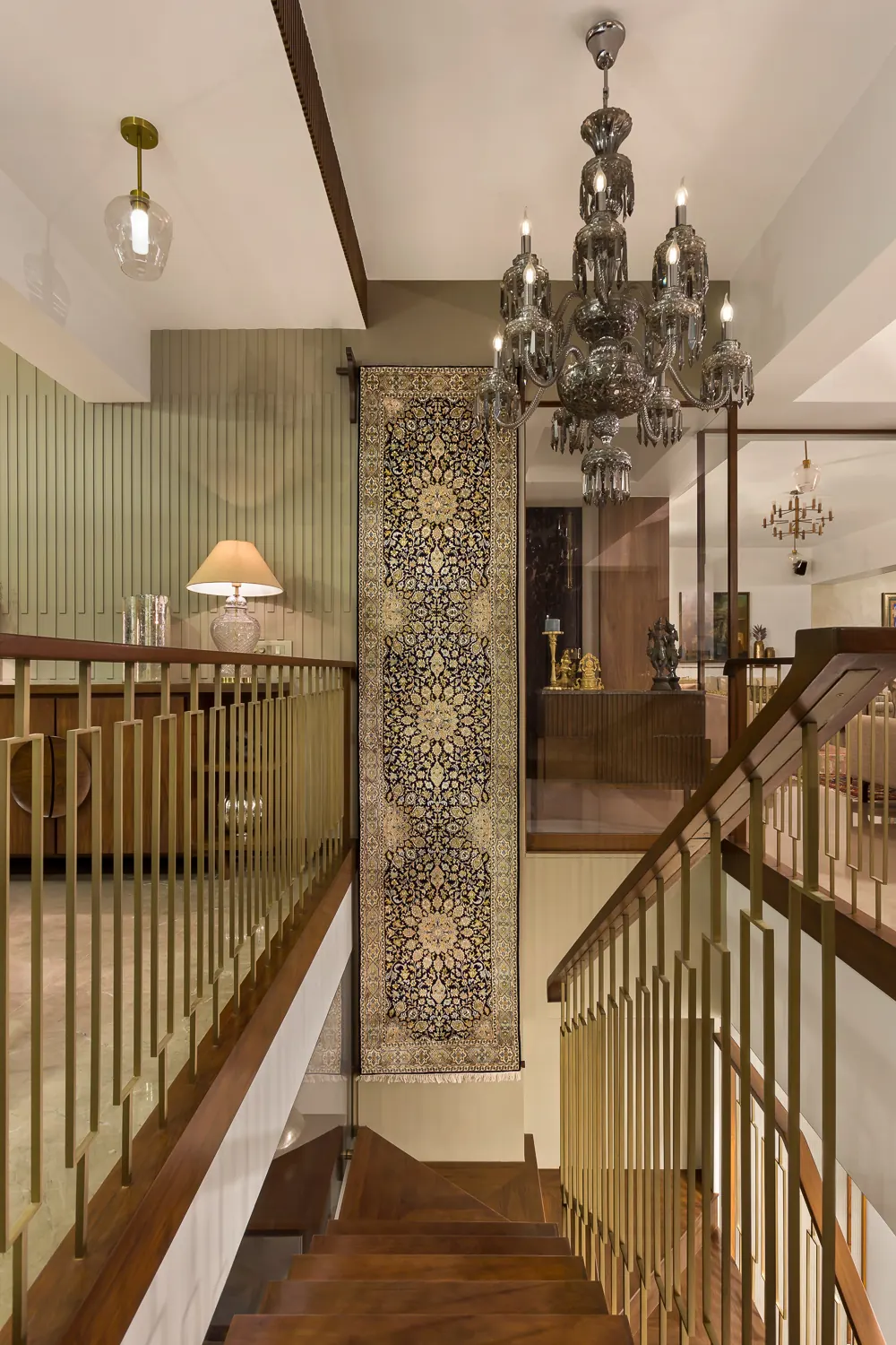 Stair landing at Zara with a hanging textile runner, a smoked-glass chandelier and dark wood panelling.