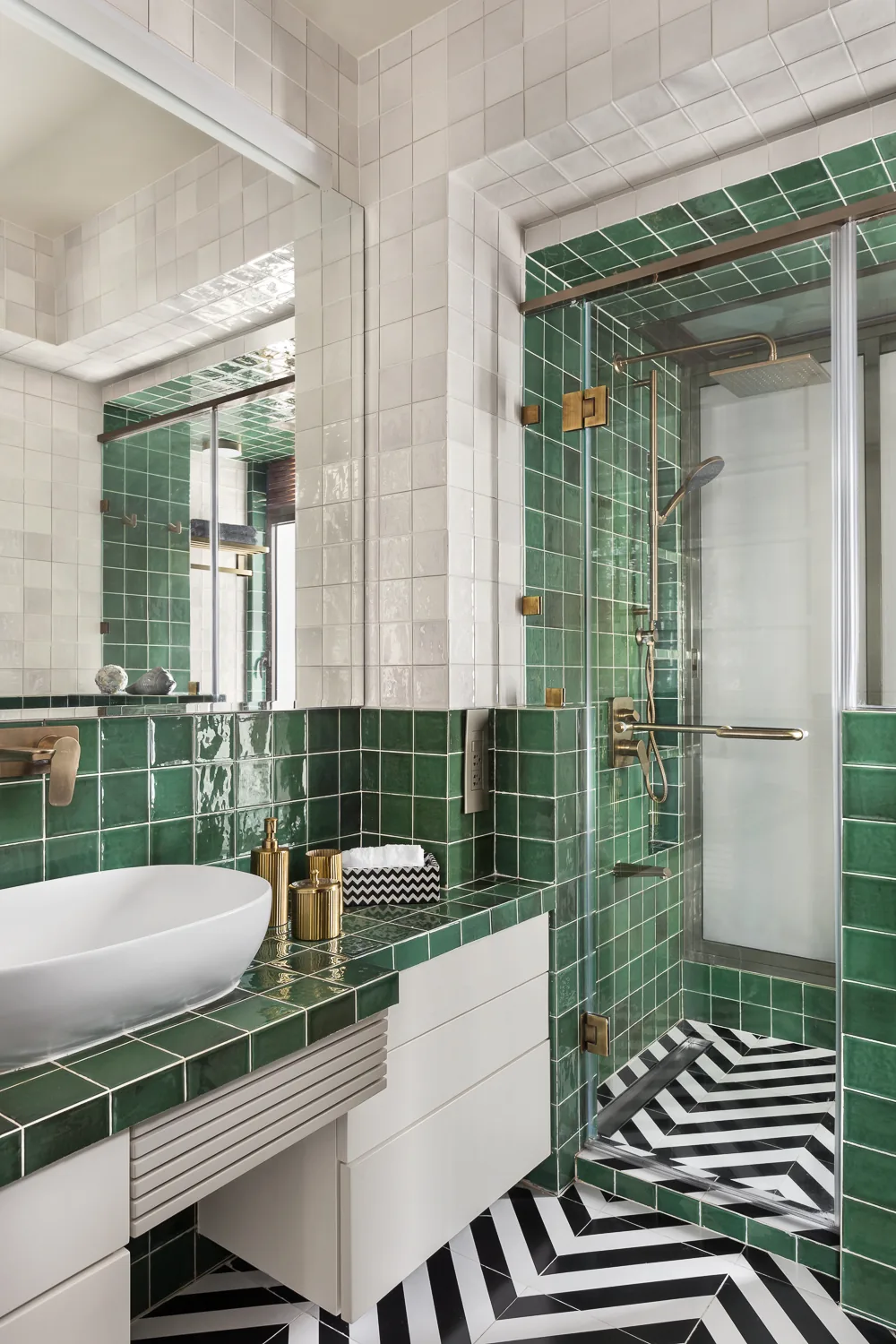 Bathroom at Zara in handmade green and white glazed tiles, with brushed brass fittings and a black-and-white chevron floor.